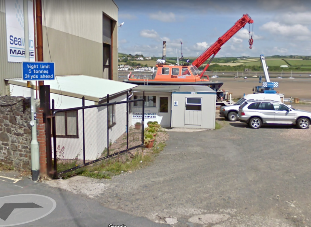 A low white building with a flat roof. Industrial equipment around.