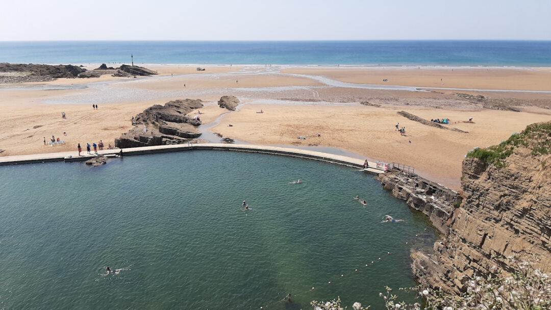 An artificial sea swimming pool at the edge of a wide sandy beach