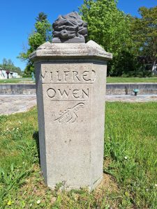 A low pillar of light-coloured stone inscribed "Wilfred Owen"