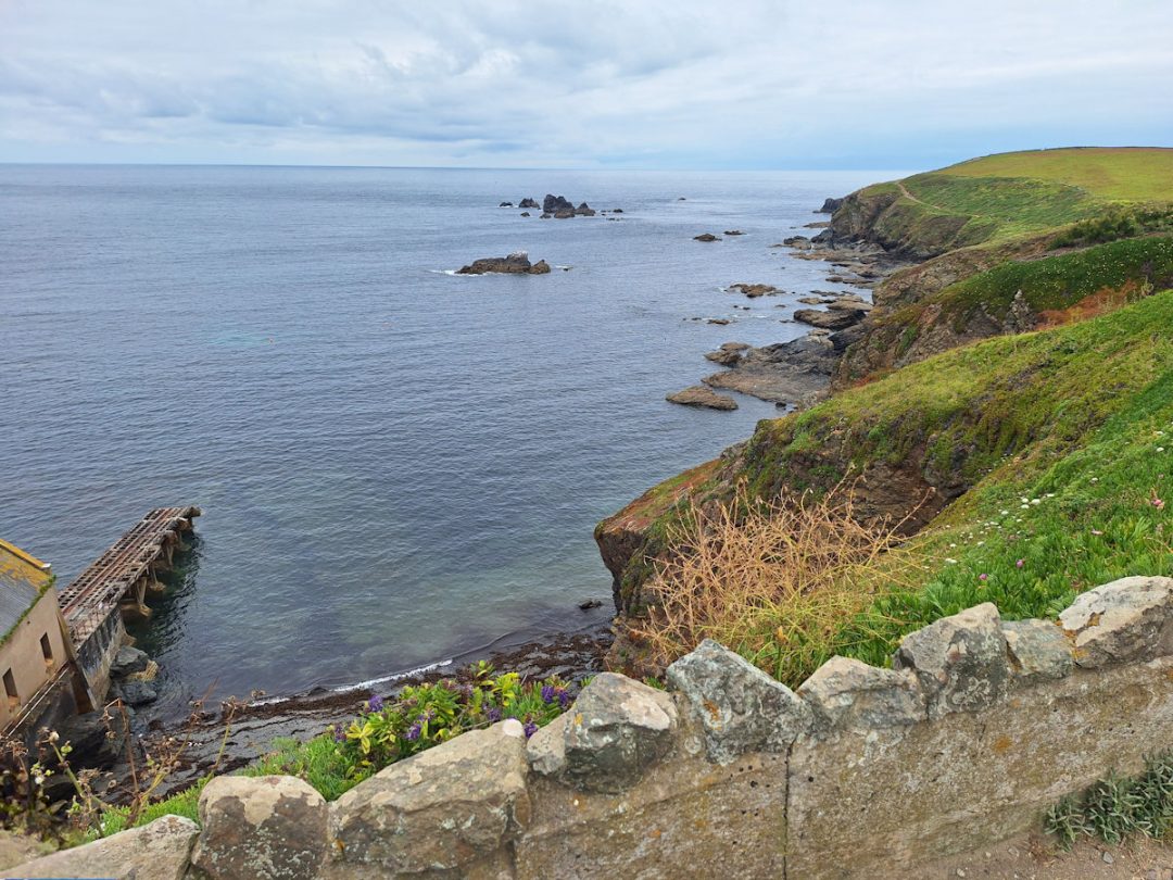 A coastline with blue sea and sky; scattered rocks in the sea.