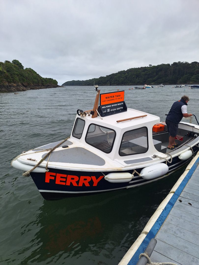 A small blue and white boat at a jetty. It has the word "FERRY" in bright orange letters on its bow.