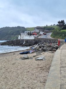 A low building on rocks above a beach.