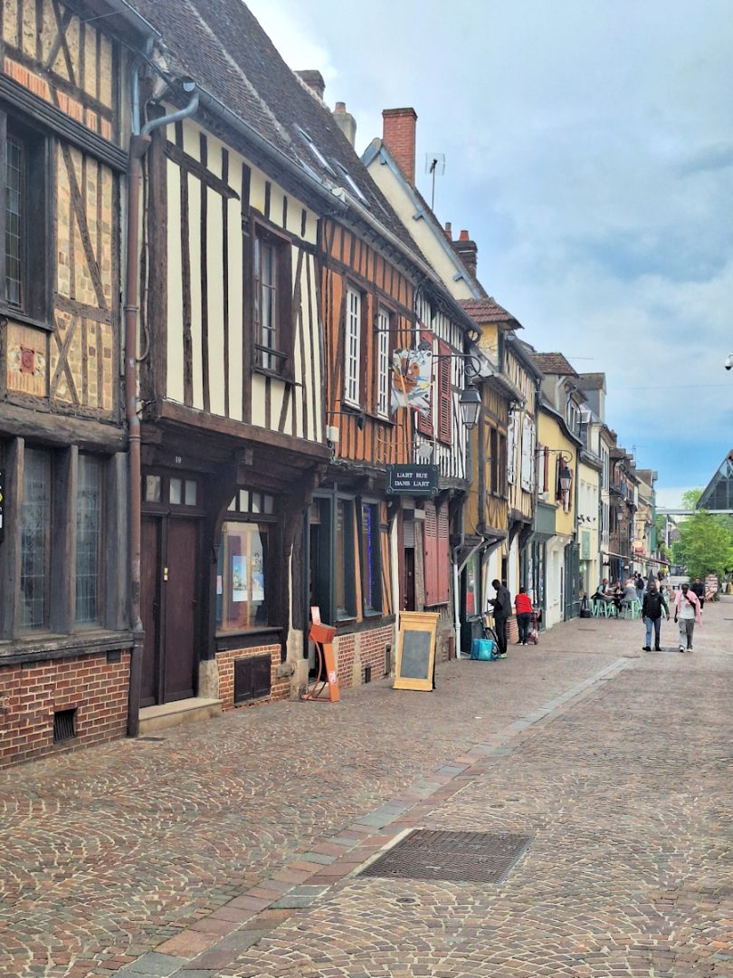 A street of half-timbered medieval houses, several converted into shops.