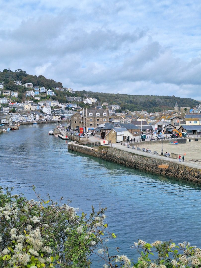A river with houses and other buildings on either side, under a cloudy sky.